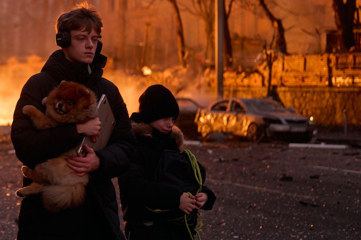 Civilians carry a dog and belongings after a Russian ballistic missile strike on the city center in Kyiv, Ukraine