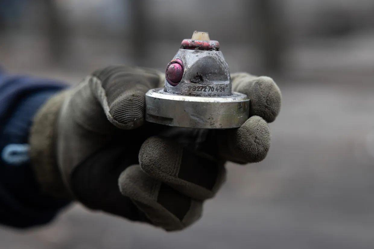 A Ukrainian deminer from the State Emergency Service shows a cluster bomb fragment after a large-scale Russian attack on a residential complex in Dobropillia, Ukraine, in March 2025
